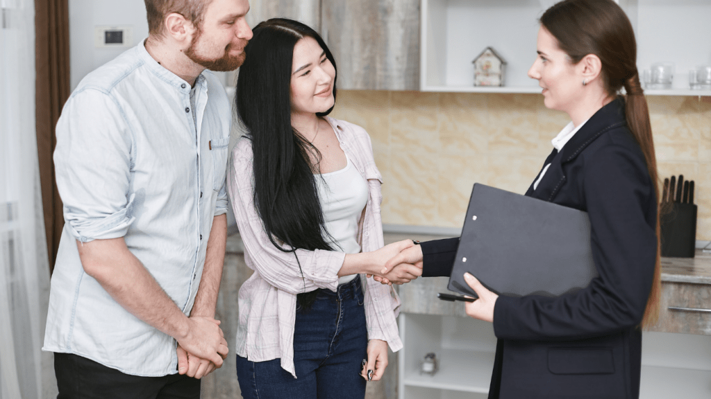 a couple shaking hands with a real estate agent