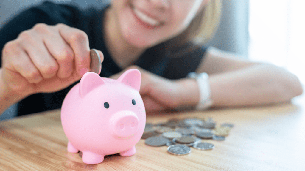 A person putting coins into a piggy bank at the table