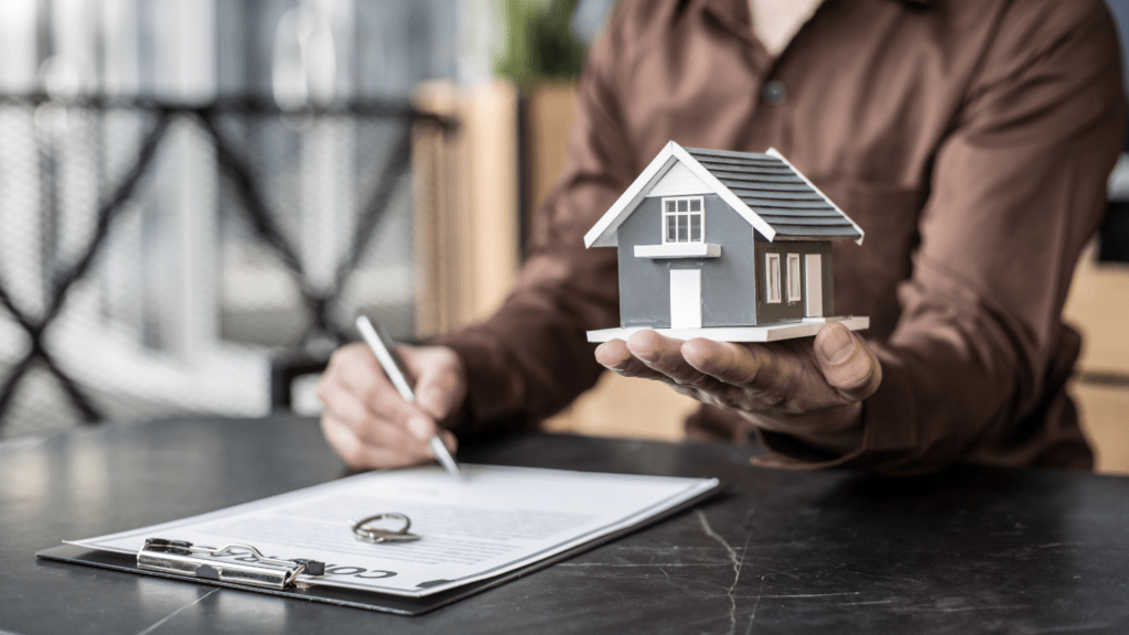 a real state agent holding a model of a house