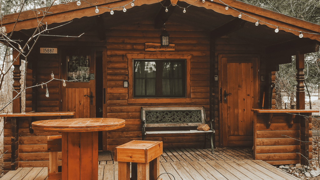 a cabin in the woods with a table and chairs on the deck