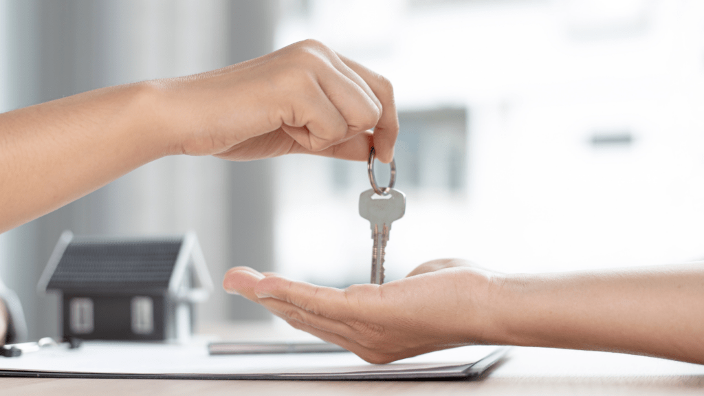 a person handing a key to another person in front of a house