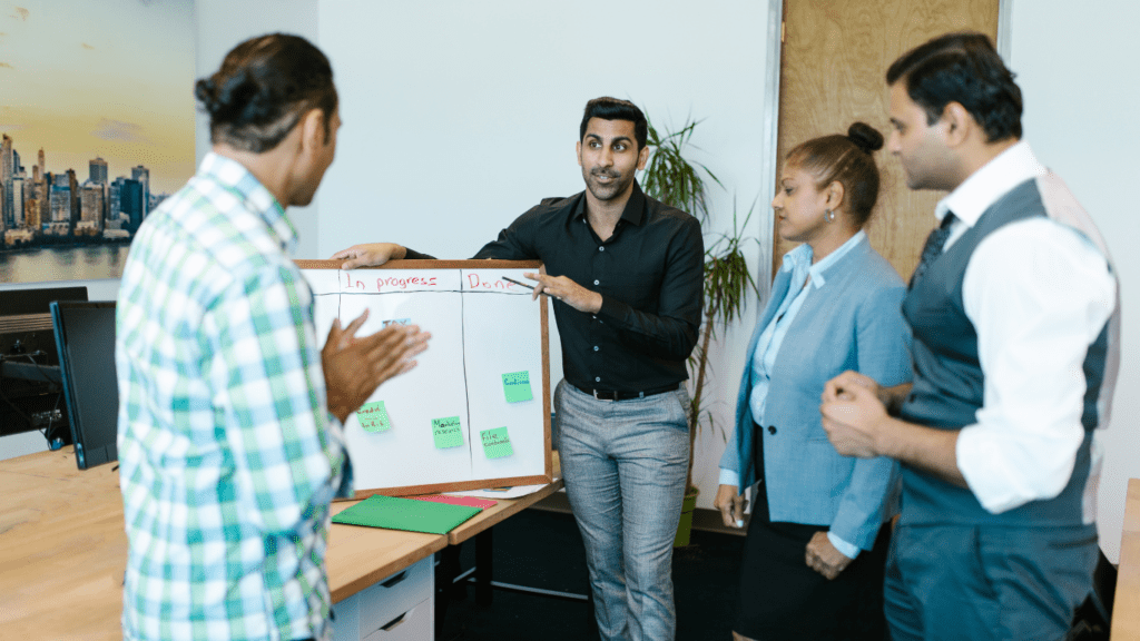 a group of people standing around a whiteboard in an office