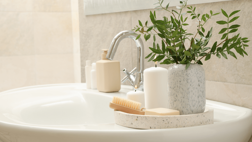 a bathroom sink with soap, toothbrush and potted plant