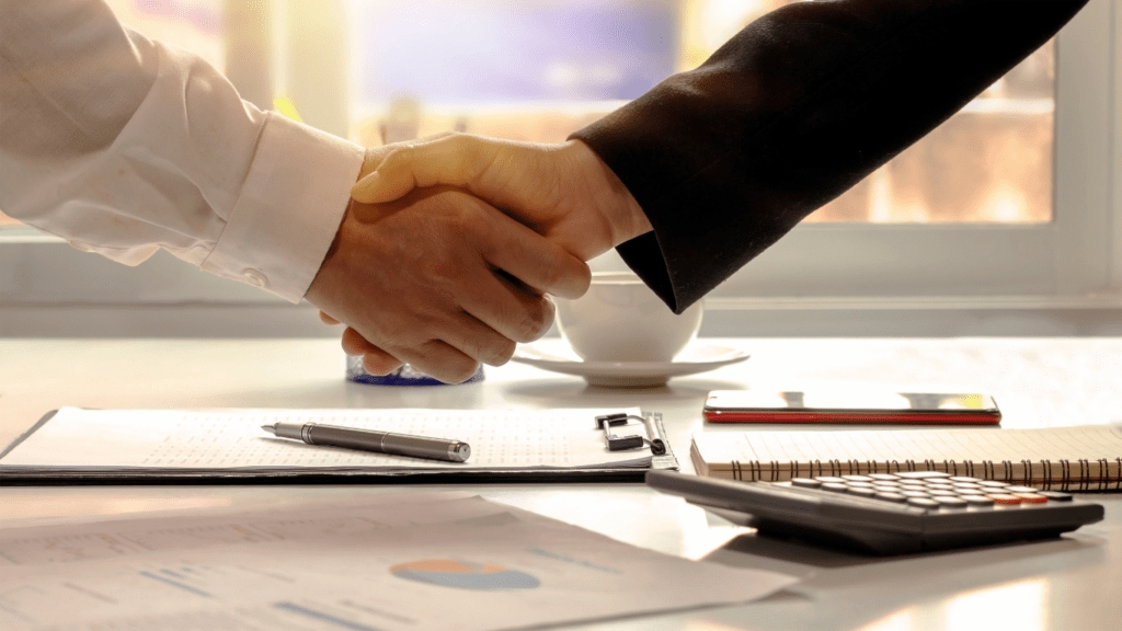 Two business people shaking hands over a desk