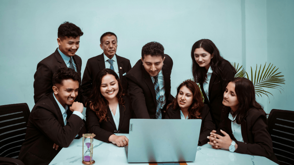 a group of business people in suits and ties looking at a laptop