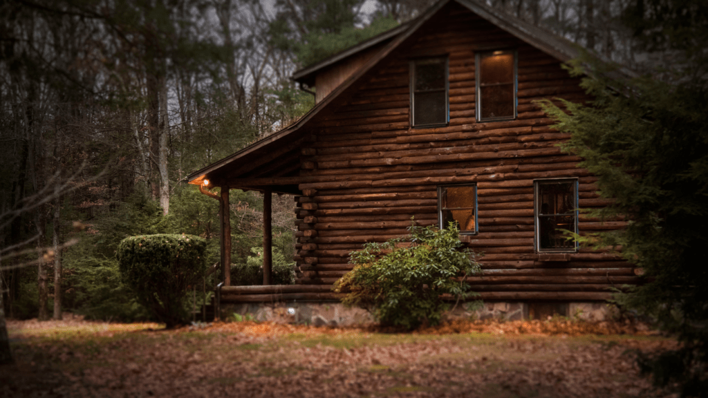 a cabin in the woods with a table and chairs on the deck