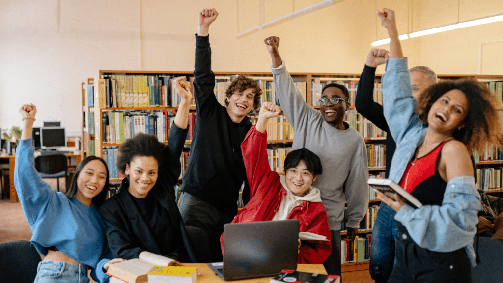 a group of people sitting around a table raising their hands