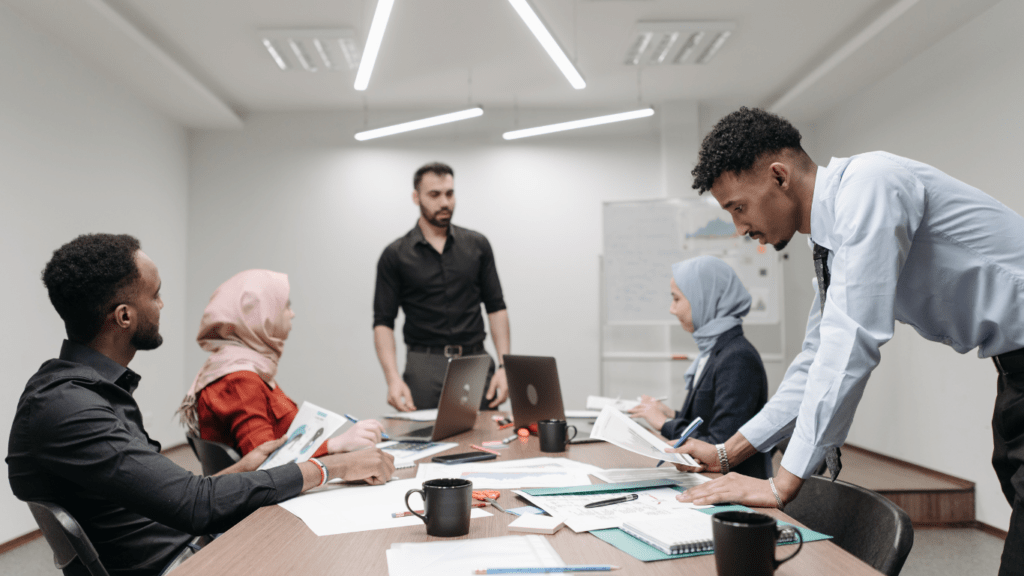 a group of people standing around a whiteboard in an office