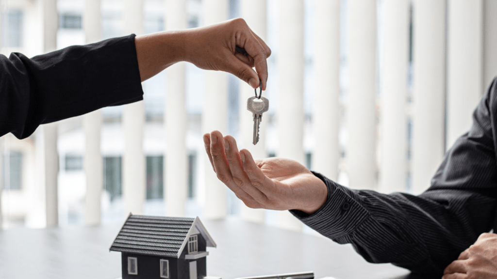 a person handing a key to another person in front of a house