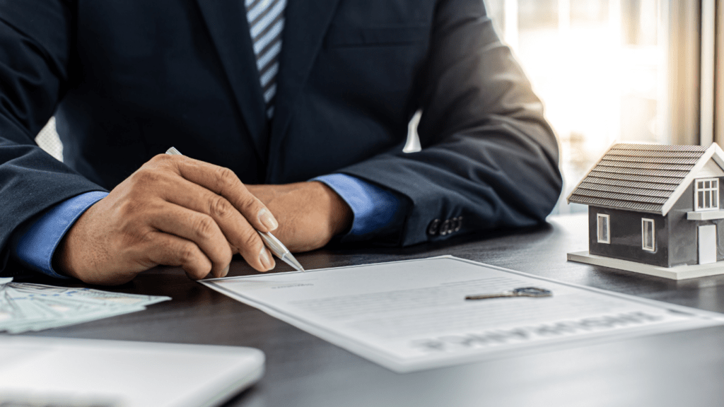 a person in a suit is signing a contract on a piece of paper