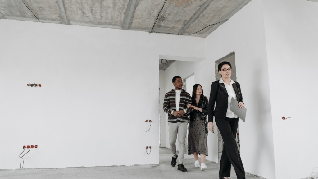 three people standing in front of a window in an apartment