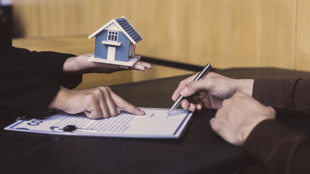 two people sitting at a table with a house model in front of them